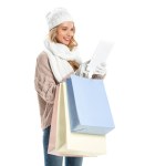 Alışveriş torbaları üzerinde beyaz izole dijital tablet kullanarak çekici genç kadın