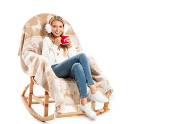 Kahve Kupası beyaz izole battaniye ile sallanan sandalyede otururken tutan genç gülümseyen kadın
