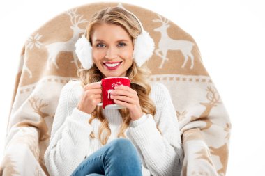 beautiful smiling woman holding cup with hot drink and sitting in armchair isolated on white clipart