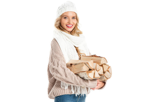 happy young woman in winter hat and scarf holding firewood isolated on white