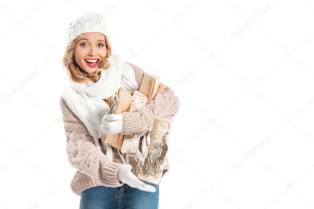 cheerful young woman in winter outfit holding firewood isolated on white