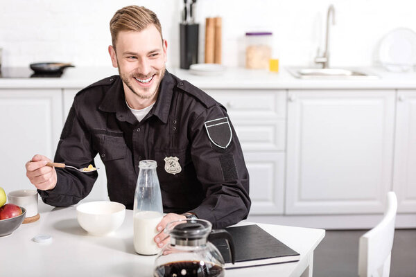 smiling policeman eating cornflakes with milk at kitchen table