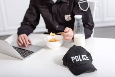 dizüstü bilgisayar kullanarak ve mutfak masada Mısır gevreği yemek polis kırpılmış görünümünü