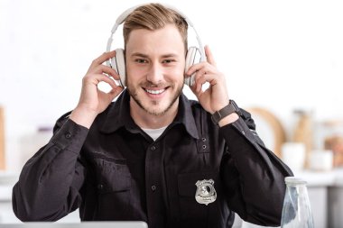 Polis gülümseyen ve mutfak at kulaklık ile müzik dinlemek