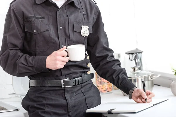 Policial Bebendo Café Escrevendo Notebook Mesa Cozinha — Fotografia de Stock