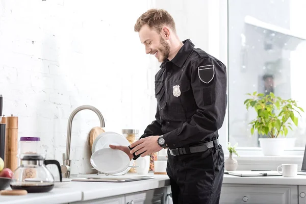 微笑的警察在厨房洗盘子 — 免费的图库照片