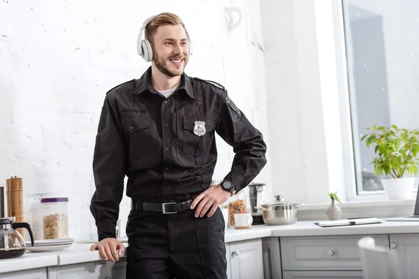 Uśmiechnięty Policjant Słuchanie Muzyki Przez Słuchawki Kuchni — Darmowe zdjęcie stockowe
