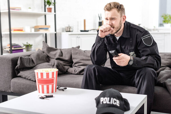 policeman with scared face expression sitting on couch and watching movie