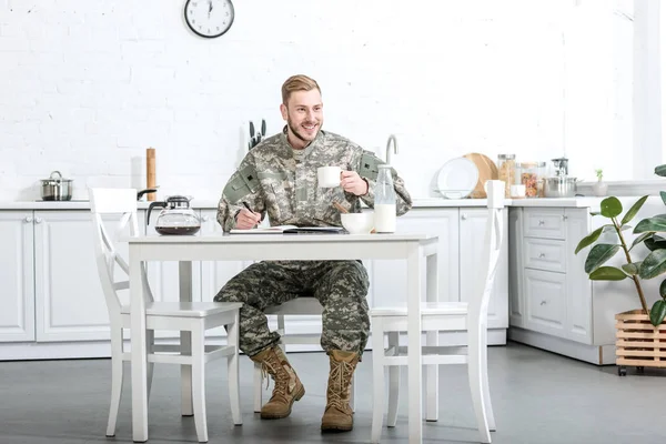 Beau Homme Uniforme Camouflage Écrivant Dans Cahier Prenant Petit Déjeuner — Photo