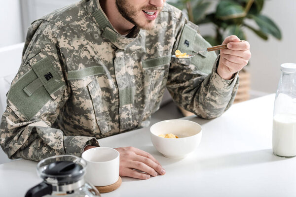 cropped view of man in camouflage uniform having breakfast in morning