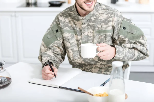 Muž Vojenské Jednotné Pití Kávy Psaní Poznámkovém Bloku — Stock fotografie zdarma