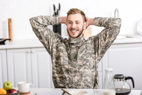 Soldado Exército Sorridente Sentado Mesa Cozinha Com Mãos Cabeça Tomando — Fotos gratuitas