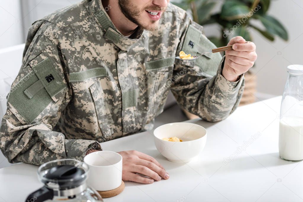 cropped view of man in camouflage uniform having breakfast in morning