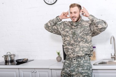 kulaklıklar giyen ve mutfak, müzik dinleme askeri üniformalı yakışıklı asker