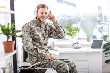 müzik dinleme ve evde mutfak tezgah üzerinde oturan kulaklıklar yakışıklı asker