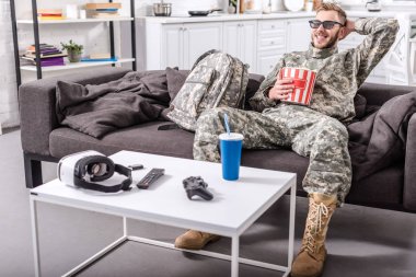 3d gözlük takan, patlamış mısır yemek ve kanepe film izlerken askeri üniformalı ordu asker