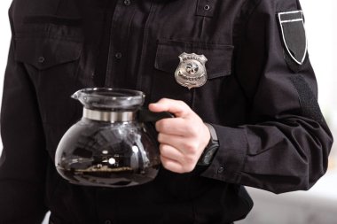 cropped view of police officer holding glass pot of hot filtered coffee clipart