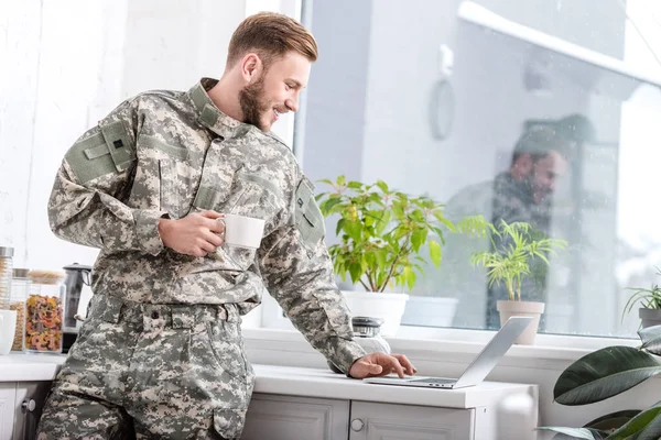 Handsome Army Soldier Holding Cup Hot Coffee Using Laptop Kitchen — Stock Photo, Image