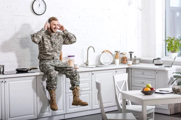 Soldado Sonriente Auriculares Escuchando Música Sentado Encimera Cocina Casa — Foto de stock gratis