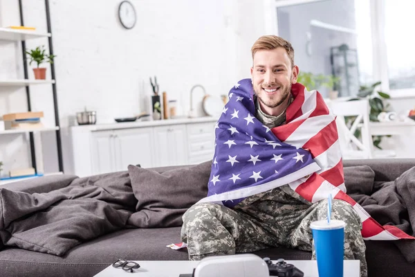 Leende Soldat Omfattas Amerikanska Flaggan Sitter Soffan Och Titta Fotboll — Stockfoto