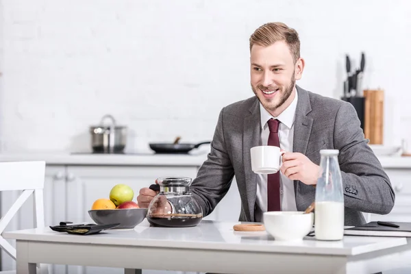 Lächelnder Geschäftsmann Trinkt Kaffee Küchentisch — kostenloses Stockfoto