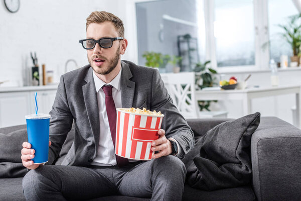 businessman on couch in 3d glasses with popcorn and soda water watching movie at home