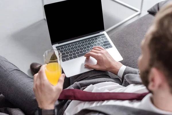 Обрезанный Вид Бизнесмена Пьющего Апельсиновый Сок Использующего Ноутбук Чистым Экраном — Бесплатное стоковое фото