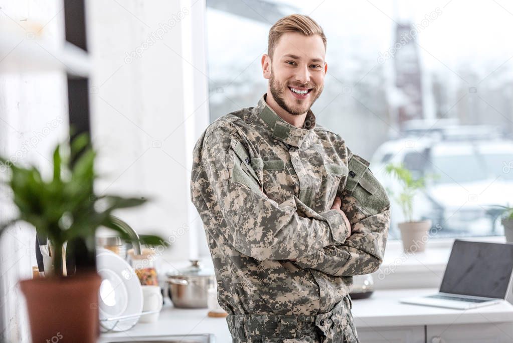 handsome soldier smiling and looking at camera in kitchen