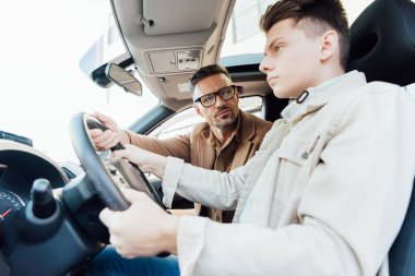 handsome father helping teen son driving car clipart