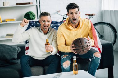 sürpriz oğlu ve hafta sonları evde basketbol maçı izlerken Amerika Birleşik Devletleri bayrağı sarılı Olgun Baba