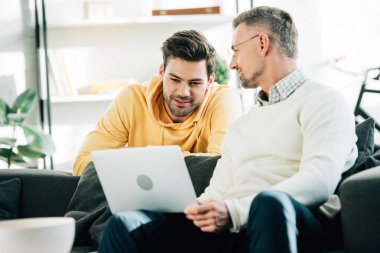 yakışıklı oğlu Olgun Baba evde kanepede dizüstü kullanarak bakarak