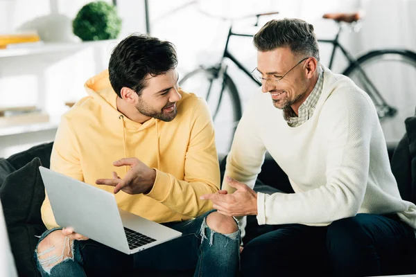 Oğlum bir şey gülümseyen Olgun Baba evde kanepede dizüstü bilgisayarda gösterilen