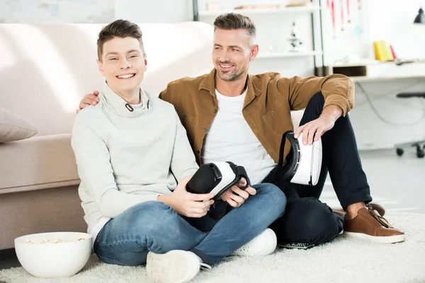 快乐的父亲和十几岁的儿子拿着虚拟现实耳机在家里 — 免费的图库照片