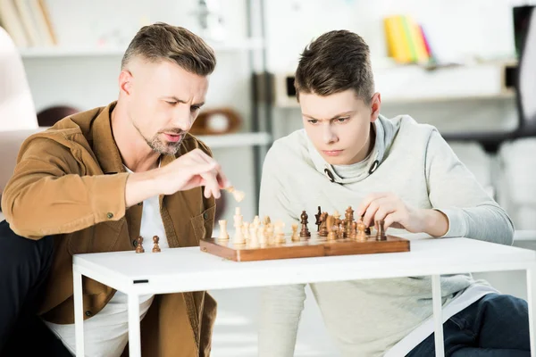 Allvarlig Far Och Tonåring Son Spelar Schack Hemma — Stockfoto