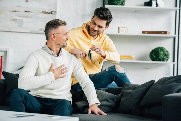 Son Presenting Car Key Surprised Mature Father Weekend Home — Stock Photo, Image