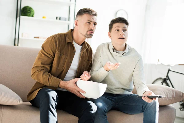 Vážný Otec Dospívající Syn Sledování Televize Doma Drží Misku Popcornu — Stock fotografie