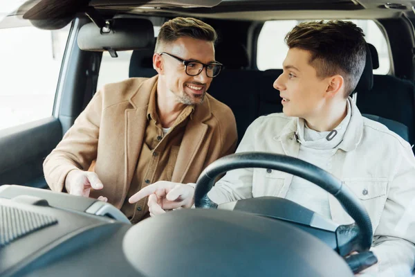 Smiling Handsome Father Teaching Teen Son Driving Car Looking Each — Stock Photo, Image