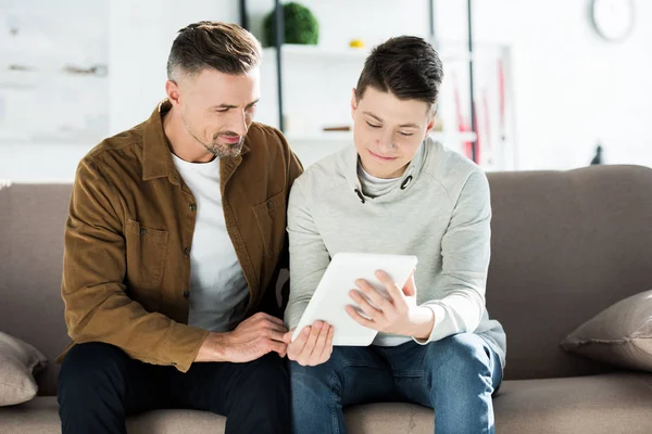 Far Och Tonåring Son Använder Surfplatta Och Sitter Soffan Hemma — Stockfoto