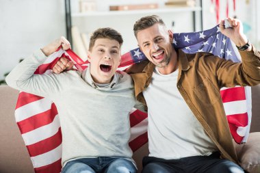 heyecanlı baba ve genç oğlu kanepede spor maç sırasında çığlık Amerika Birleşik Devletleri bayrağı sarılı