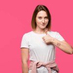 Cheerful stylish girl showing thumb up gesture isolated on pink