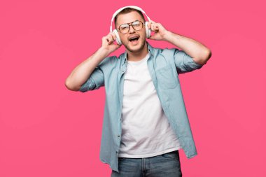 kulaklıklar müzik dinleme ve pink izole kamera gülümseyen gözlük mutlu genç adam 