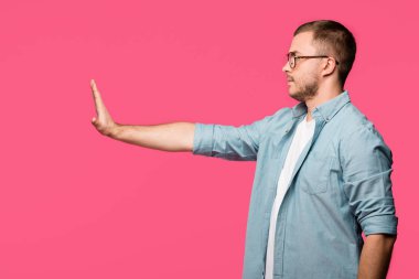 side view of man gesturing no with hand and looking away isolated on pink clipart