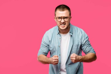 saldırgan genç adam yumruk sallayarak ve pink izole kamera bakıyor