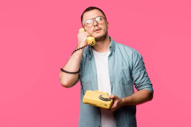 Genç adam döner telefonla konuşurken ve ararken pink izole gözlük