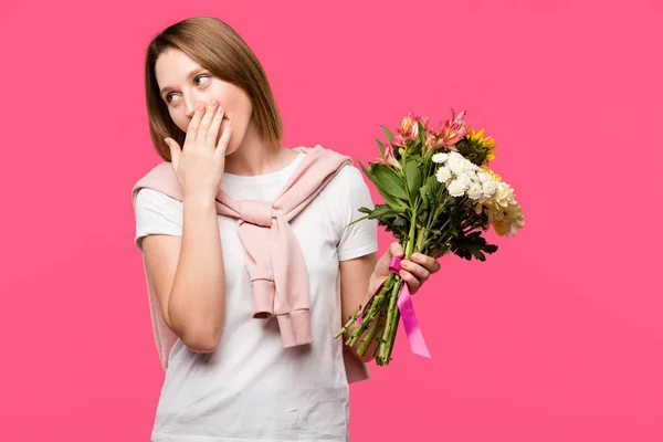 女孩用手捂住嘴 拿着五颜六色的花束从各种花隔离在粉红色 — 免费的图库照片