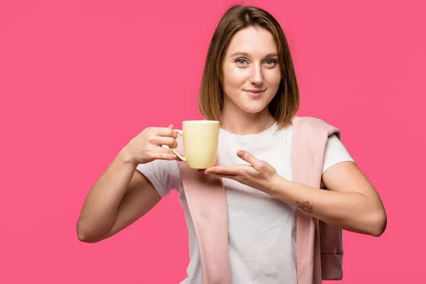 Bella Giovane Donna Tenendo Tazza Sorridente Alla Fotocamera Isolata Rosa — Foto stock gratuita