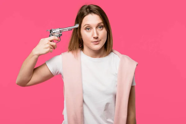 Revolver Kafa Yakın Tutarak Pink Izole Kamera Bakarak Genç Kadın — Ücretsiz Stok Fotoğraf