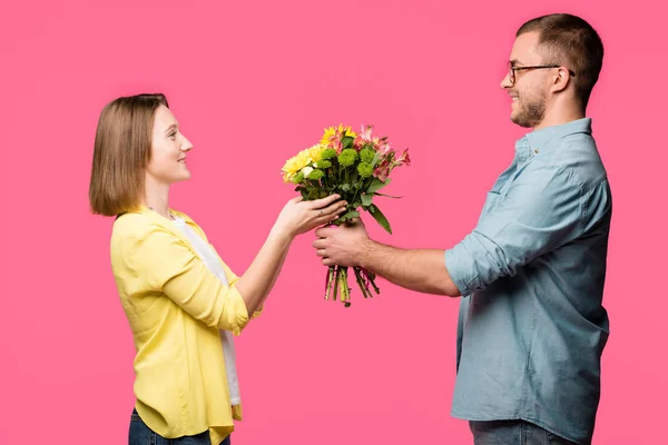 Vista Lateral Feliz Pareja Joven Sosteniendo Ramo Flores Aislado Rosa — Foto de stock gratuita