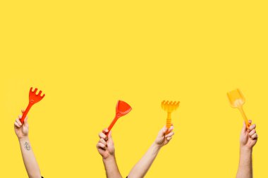 kırmızı ve sarı plastik kürek ve sarı izole tırmıklar holding erkek ve dişi eller kırpılmış atış