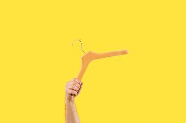 cropped shot of person holding wooden hanger isolated on yellow clipart
